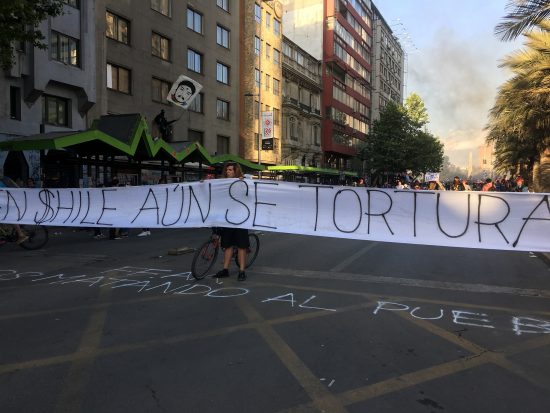 「チリはいまだに拷問を続けている」と書かれた横断幕