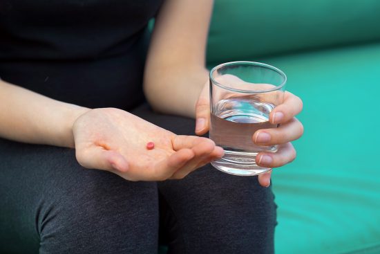 Woman drinks a pill from pain